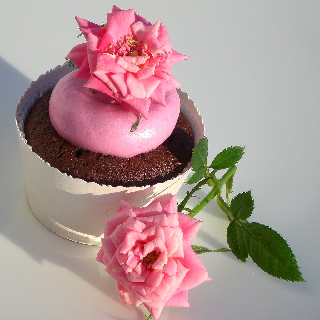 ピンクのバラを添えたカップケーキの写真